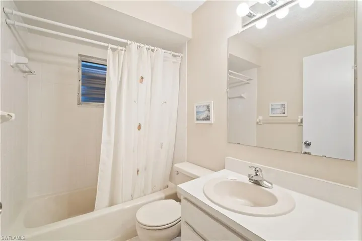 Full bathroom featuring shower / bath combo, a textured ceiling, vanity, and toilet