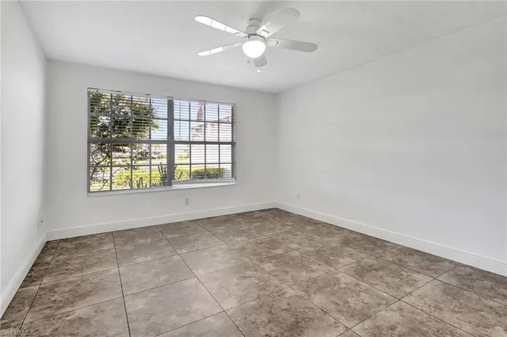 Master bedroom featuring a ceiling fan and light tile patterned floors.