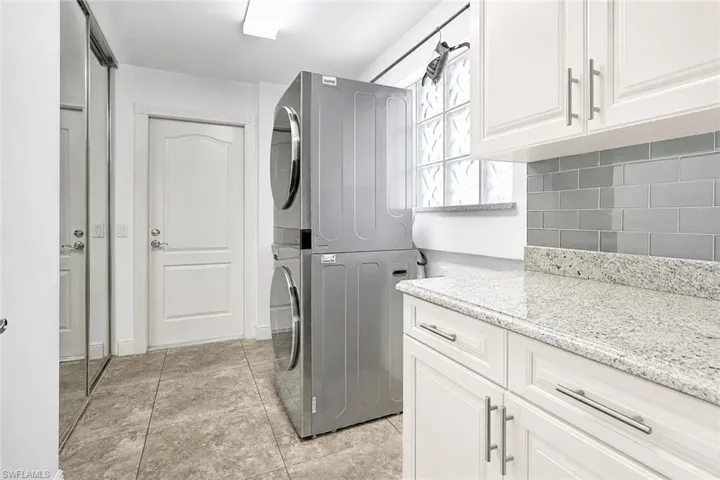 Staged photo cabinets painted in off-white Laundry area featuring white cabinetry, light granite-finish countertops, and a gray subway tile backsplash