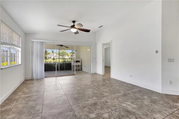 Dining  room + open den with vaulted ceiling, a ceiling fan, and light tile patterned floors.