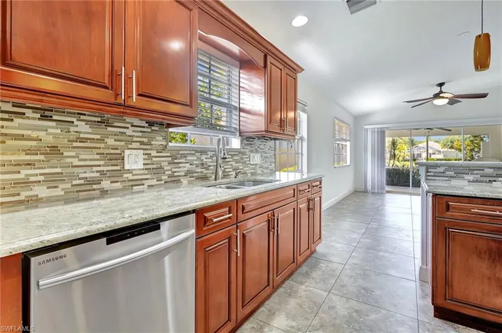 Kitchen with stainless steel dishwasher, light stone counters, plenty of natural light, ceiling fan, and recessed lighting
