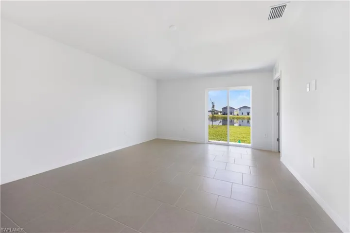 Tiled empty room featuring a water view and baseboards
