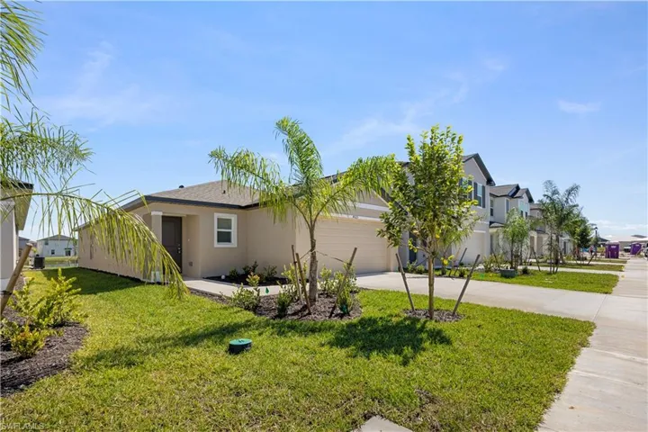 View of side of home featuring driveway, a yard, stucco siding, and an attached garage