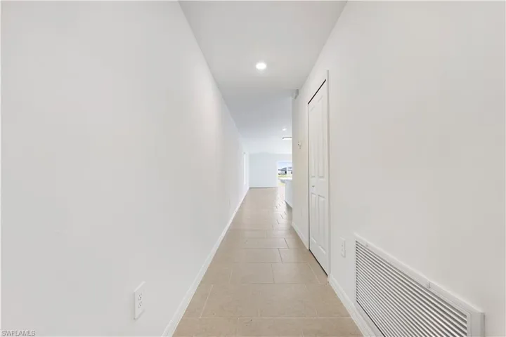 Corridor with light tile patterned flooring and recessed lighting