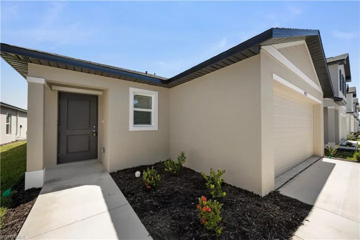 Property entrance featuring stucco siding, an attached garage, and driveway
