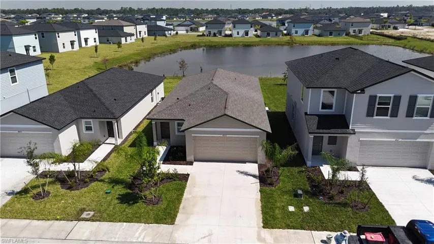 View of front of house with stucco siding, a water view, concrete driveway, a residential view, and roof with shingles