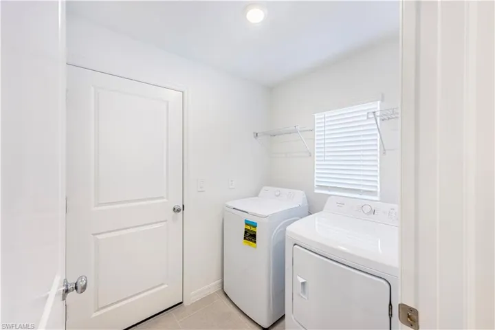 Washroom featuring light tile patterned flooring and washer and dryer
