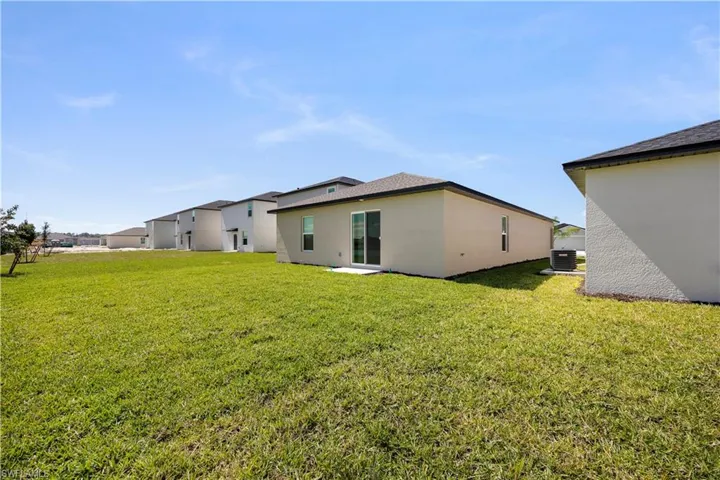 Rear view of property featuring stucco siding and a yard