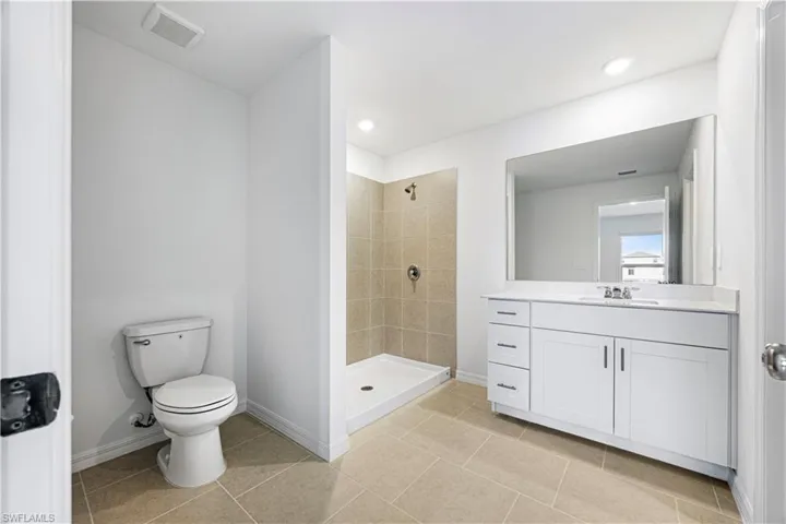 Full bathroom with vanity, a shower stall, light tile patterned floors, and recessed lighting