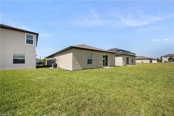 Rear view of house featuring a yard and stucco siding