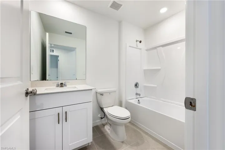 Bathroom with shower / tub combination, light tile patterned floors, and vanity