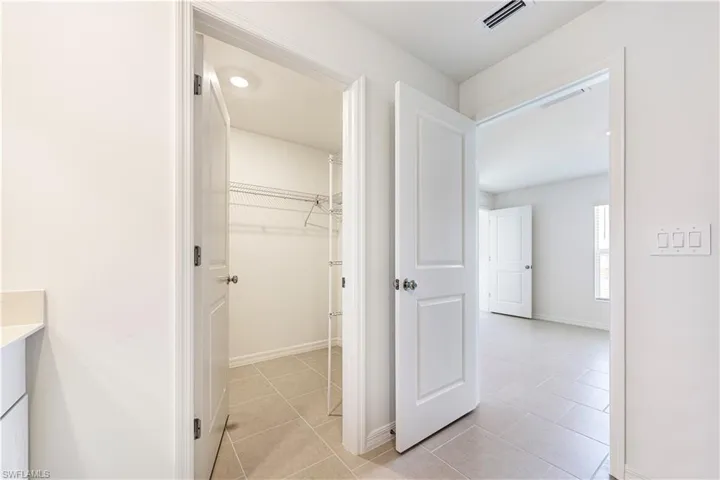 Hall featuring light tile patterned floors and baseboards
