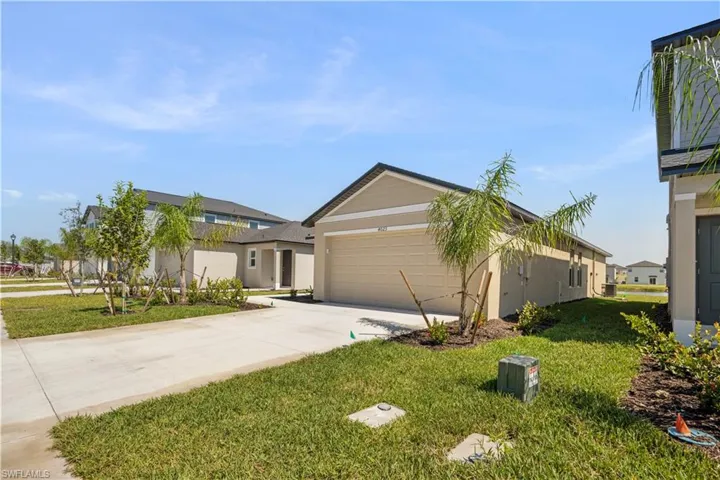 View of front of house featuring driveway, a front lawn, an attached garage, and stucco siding