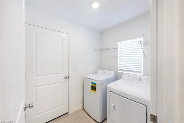 Laundry area featuring light tile patterned floors and washing machine and dryer