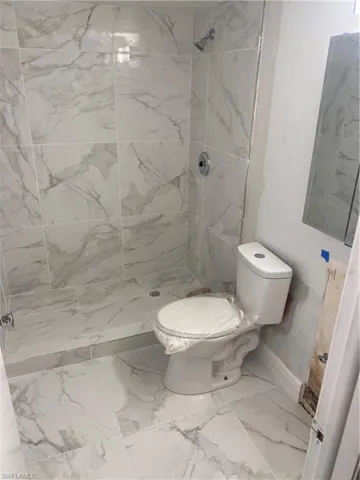 Bathroom featuring a tile shower and toilet