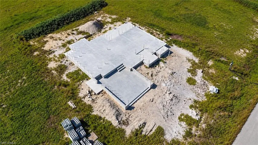 Poured concrete foundation with structural steel reinforcement components on a cleared lot