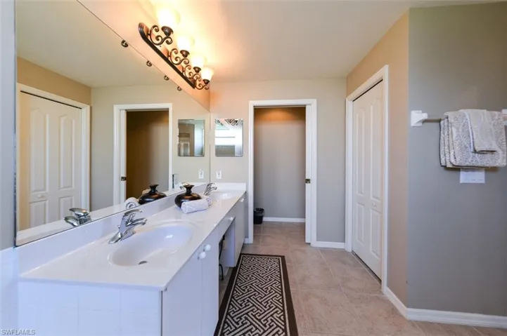 Bathroom featuring double vanity, light tile patterned floors, and a closet