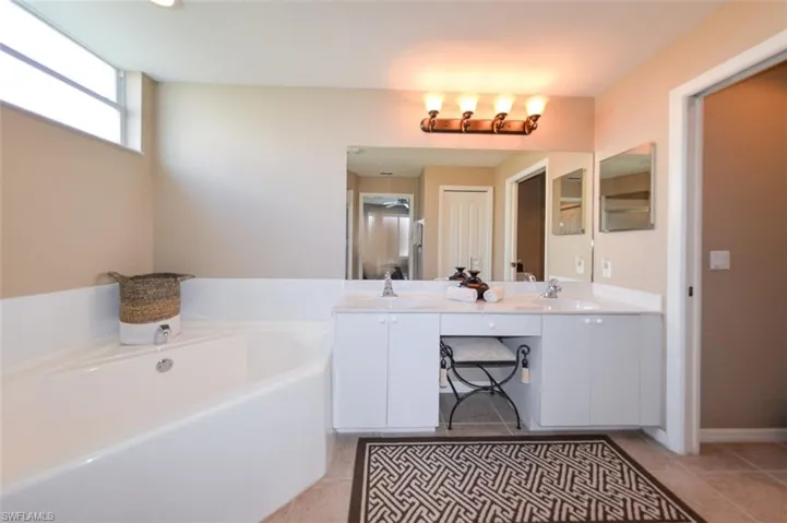 Bathroom with double vanity, a garden tub, and light tile patterned floors
