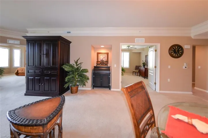 Living area featuring crown molding, light colored carpet, and a ceiling fan