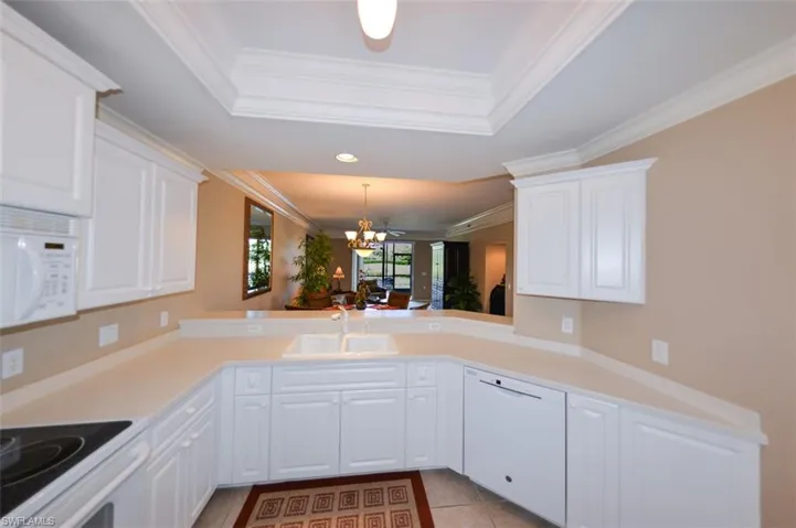 Kitchen with white cabinetry, white appliances, a chandelier, decorative light fixtures, and light countertops