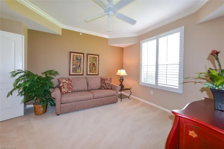Carpeted living area featuring crown molding and ceiling fan