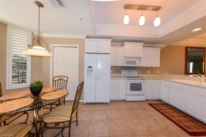Kitchen with white appliances, decorative light fixtures, white cabinetry, light countertops, and light tile patterned flooring