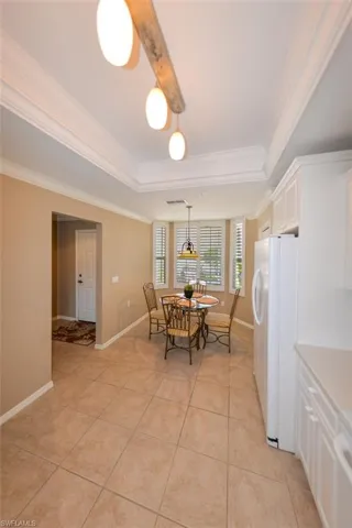 Dining space featuring crown molding, light tile patterned floors, and a tray ceiling