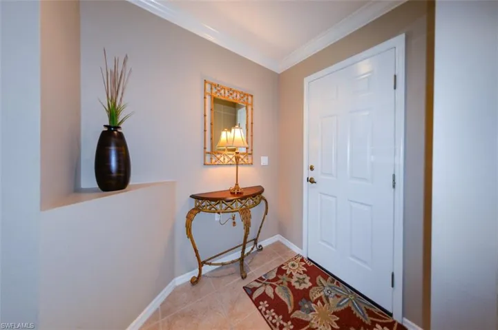 Tiled foyer entrance with crown molding and baseboards