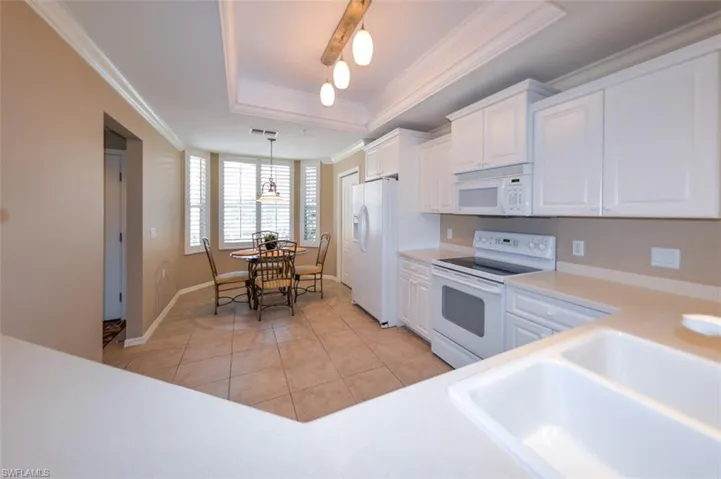 Kitchen featuring white cabinetry, white appliances, light countertops, light tile patterned flooring, and pendant lighting