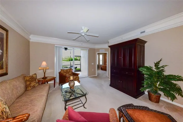 Living area featuring ornamental molding, light carpet, and ceiling fan