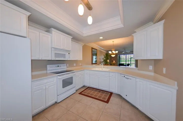 Kitchen featuring a chandelier, white appliances, white cabinets, light countertops, and ornamental molding