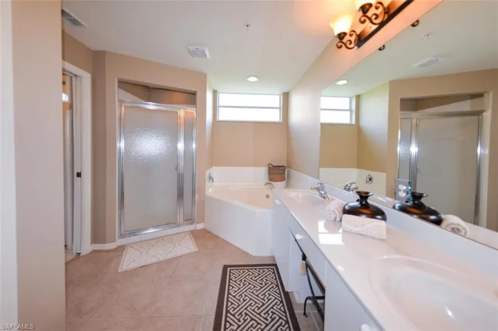 Bathroom with double vanity, a stall shower, a bath, light tile patterned floors, and recessed lighting