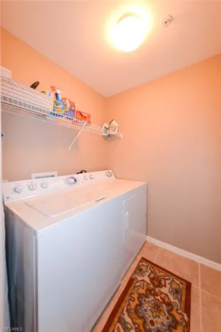 Laundry area featuring washing machine and clothes dryer and light tile patterned flooring