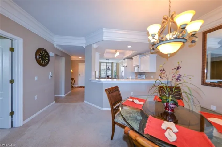Dining area featuring a chandelier, light carpet, and crown molding