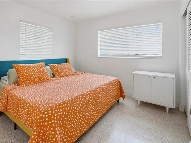 Bedroom featuring expansive window with blinds, white walls, and light-colored terrazzo flooring