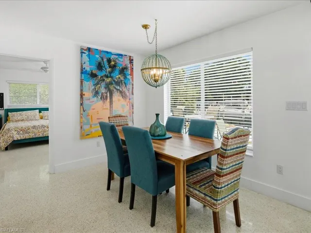 Dining area with a wood-finish table, a decorative spherical chandelier, and expansive windows