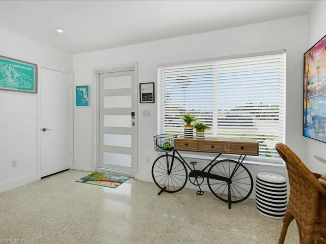Modern entry area featuring a white contemporary door with frosted glass panels, bright white walls, recessed ceiling lighting, and speckled hard-surface flooring