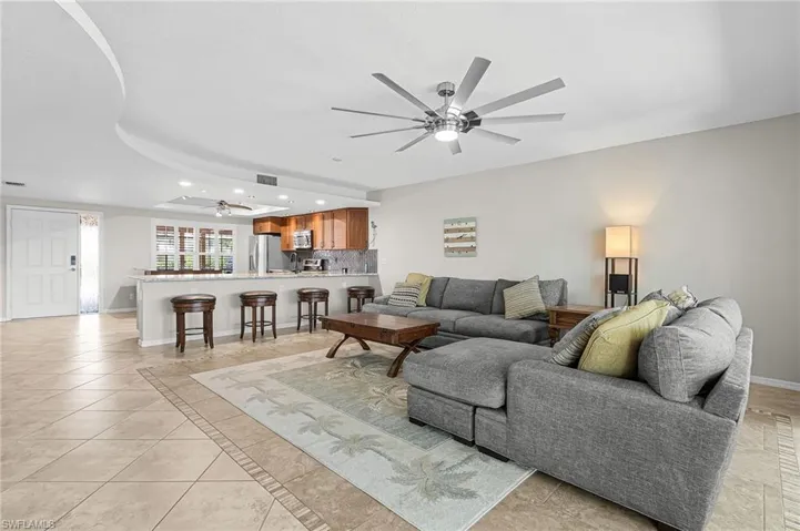 Living area featuring recessed lighting, a ceiling fan, light tile patterned floors, inlaid floor details, and a raised ceiling