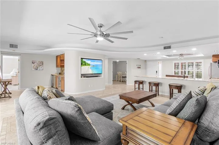 Living area featuring a raised ceiling, ceiling fan, recessed lighting, and light tile patterned floors