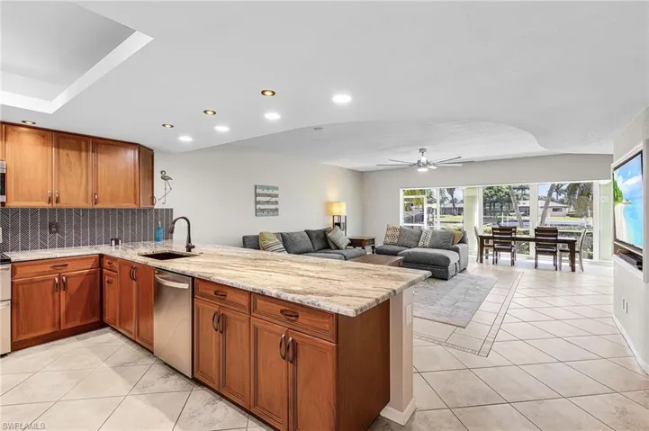 Kitchen featuring brown cabinetry, light stone countertops, light tile patterned floors, and recessed lighting