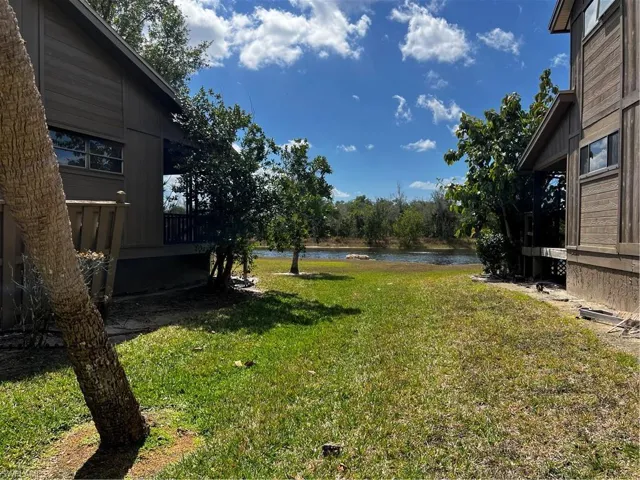 View of grassy yard featuring a deck with water view