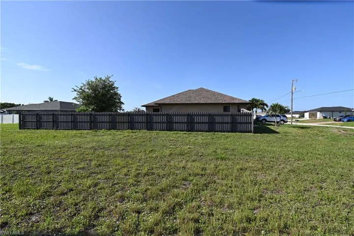 Expansive lot featuring a dark-toned privacy fence and a one-story dwelling with a hip roof