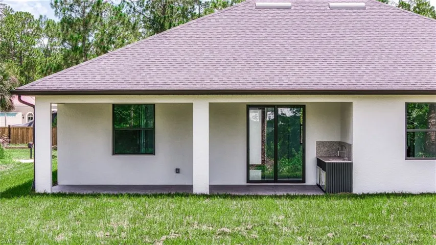 Back of property featuring stucco siding, a patio area, a shingled roof, and a yard