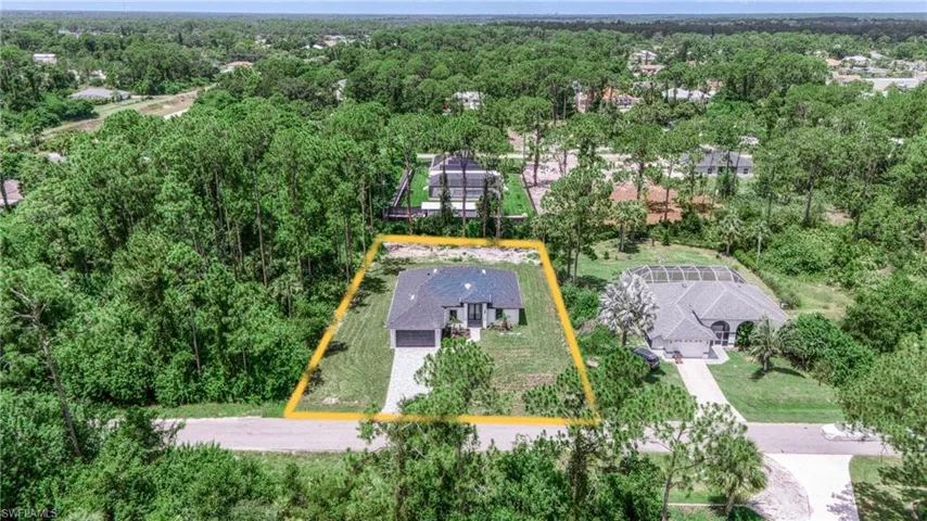 Aerial view of residential area featuring property boundaries highlighted and a heavily wooded area