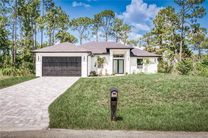 Prairie-style home with a garage, decorative driveway, a front lawn, and stucco siding