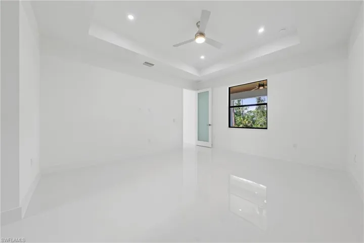 Unfurnished room featuring a tray ceiling, recessed lighting, light tile patterned flooring, and a ceiling fan
