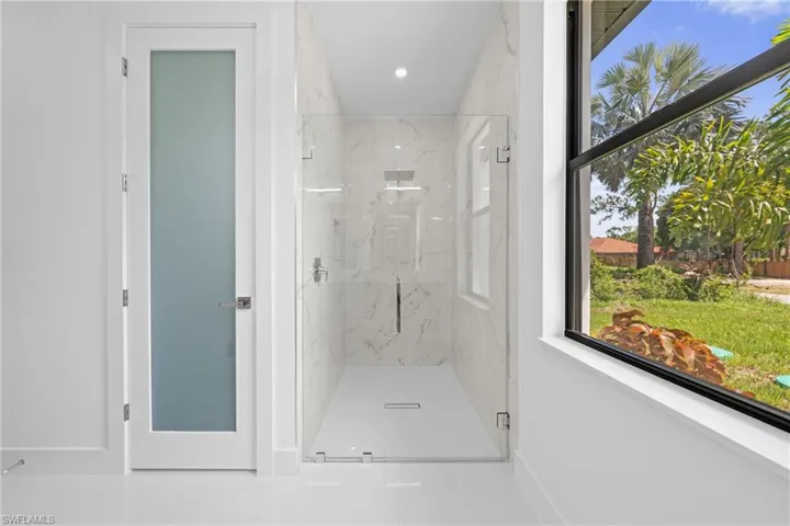 Bathroom featuring a marble finish shower, healthy amount of natural light, and recessed lighting