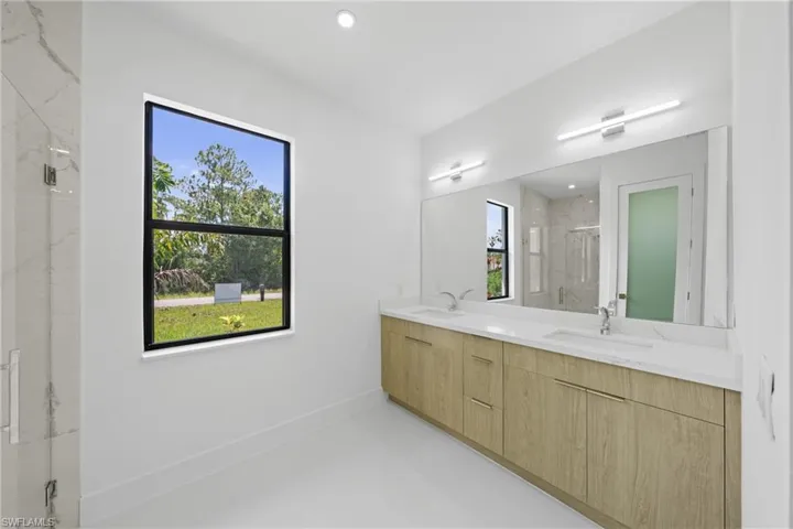 Bathroom featuring a marble finish shower, double vanity, finished concrete floors, and recessed lighting