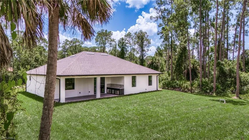 Rear view of property featuring a yard, a patio area, stucco siding, and a shingled roof