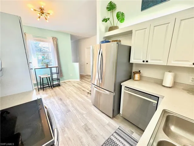 Kitchen with white cabinetry, appliances with stainless steel finishes, sink, and light hardwood / wood-style floors